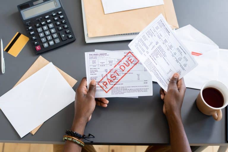 Hands of young African male holding unpaid bill over other papers and invoices